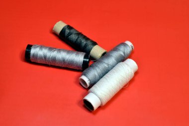 Dikiş makinesinde çalışmak için kullanılan iplik makaraları kırmızı arkaplanda uzanır.