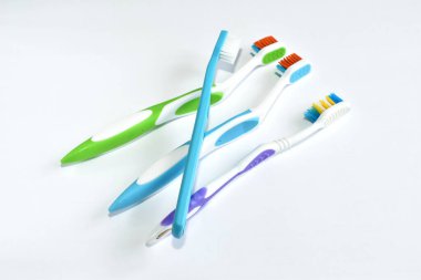 Farklı renkte diş fırçaları beyaz arkaplanda rastgele uzanır.