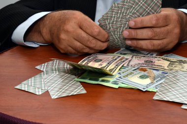 Kart oyunu, para ve kartlar masada. Oyuncu kartları elinde tutuyor..