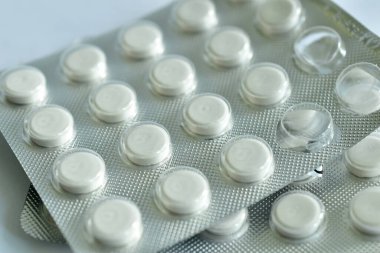 Sayısız satırla küçük boy tabletlerin açıldığı paket beyaz bir arkaplanda yatıyor..