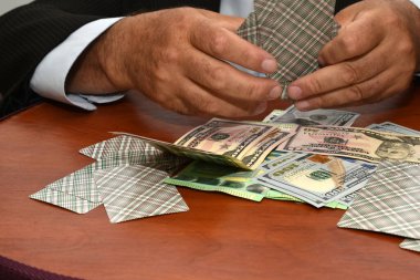 Fotoğraf, üzerinde para ve kartlar olan bir masada oturan bir kart oyuncusunun elini gösteriyor..