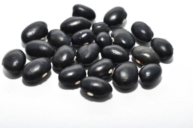 Siyah fasulye tohumları beyaz arkaplanda bir yığın halinde yatıyor..