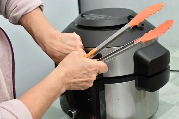 Bir kadın çoklayıcının ağır kapağını açmaya çalışır..