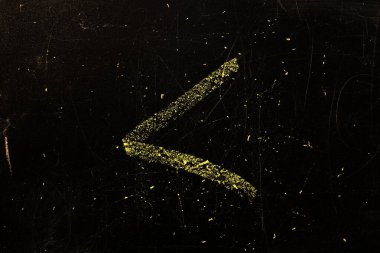 Siyah yüzeyde, daha küçük bir İngiliz alfabesi işareti tebeşirle yazılır..