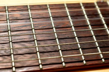 Gitarın ahşap kahverengi boynu ve telleri var. Yakın plan..