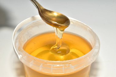 Ihlamur çiçeklerinin kalın balı kaşıktan kovaya akıyor..