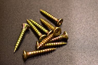 Metalle çalışmak için vidalar koyu bir arka planda yatar.