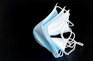 Birçok tıbbi maske siyah arka planda yatar..