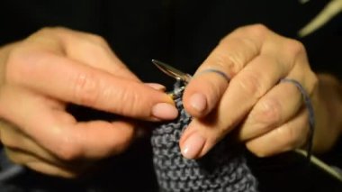 Örgü iğnesi ve yün iplik tutan bir kadının ellerinin yakın çekimi. Bir şey örüyor..