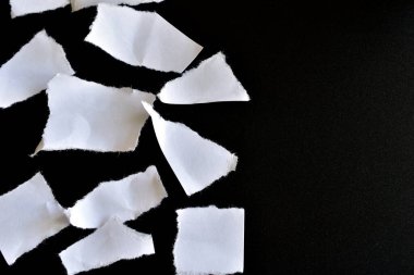 Siyah arkaplanda sayısız beyaz kağıt kırıntıları var..