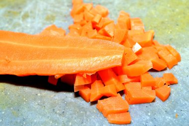 Salata için küp küp kesilmiş haşlanmış havuç masanın üzerindeki kesme tahtasının üzerinde duruyor..