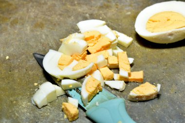 Salata için dilimlenmiş haşlanmış tavuk yumurtaları masanın üzerindeki kesme tahtasının üzerinde duruyor..