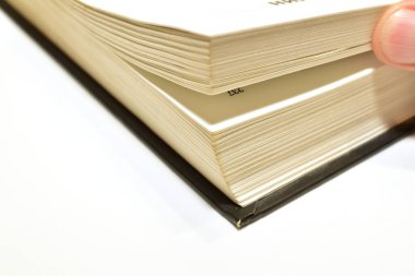 Bir adamın eli masanın üzerinde duran bir kitabın sayfalarını çevirir..