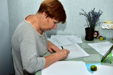 Masasında muhasebe belgeleri olan çalışan bir kadının yan görünüşü.