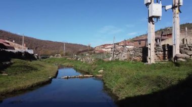  Drone kırsaldaki küçük bir nehrin üzerinden uçuyor ve antik bir taş köprünün altından geçiyor.