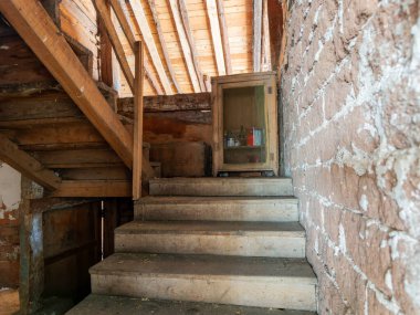 Terk edilmiş bir evde aşınmış ahşap bir merdiven, çürüme ve bozulma belirtileri gösteriyor.