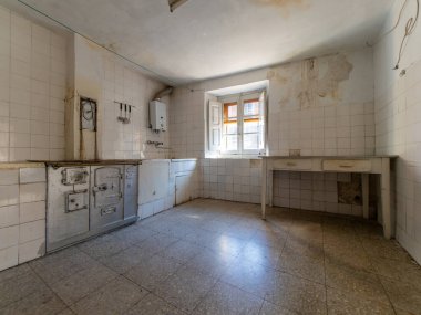 Eski soba, çürüyen alçı ve eski mobilyalar içeren terk edilmiş bir evde harap olmuş bir mutfak ihmalkarlık ve tarih hissi uyandırıyor.