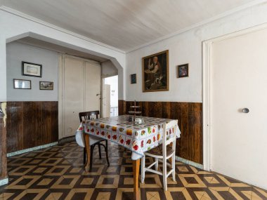 Retro desenli masa örtüsü yemek masasını ve terk edilmiş evlerin yemek odasındaki sandalyeleri klasik resimlerle kaplıyor.