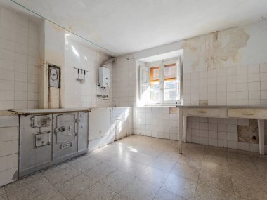 Eski terk edilmiş mutfak, hasarlı duvarlar, eski cihazlar, ve çürüme belirtileri, zamanın geçişini ve bakımsızlığın durumunu vurguluyor.