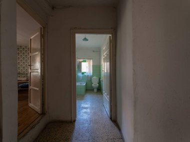 Terk edilmiş bir evin içini keşfetmek, eski bir banyo ve yatak odasını açık kapılardan açmak.