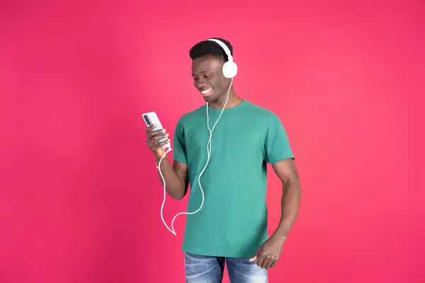 Mutlu adam kulaklıkla müzik dinliyor ve akıllı telefon uygulaması kullanarak şarkı seçiyor.