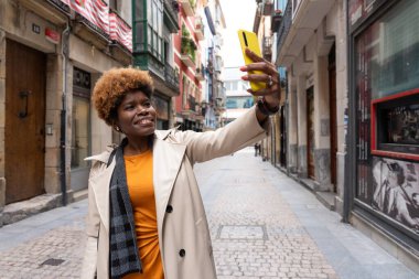 Şık bir turist akıllı telefonuyla selfie çekerken büyüleyici mimariyle dolu Avrupa sokaklarında geziniyor.