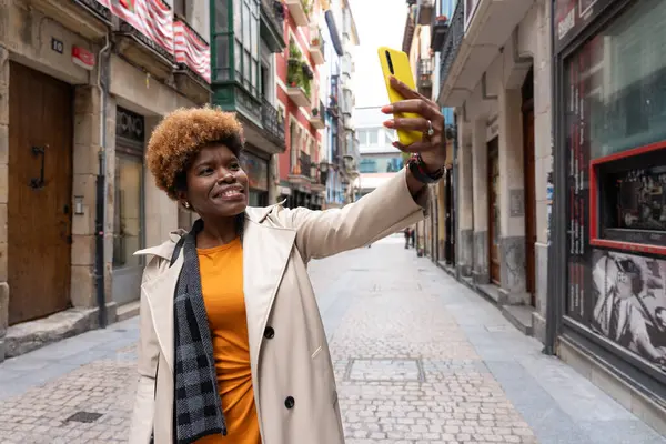 Şık bir turist akıllı telefonuyla selfie çekerken büyüleyici mimariyle dolu Avrupa sokaklarında geziniyor.