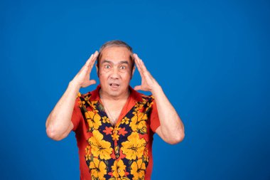 Şok olmuş bir ifadeyle endişeli, kafası tutulmuş, unutkanlık, kafa karışıklığı ya da stres tasvir eden, canlı, mavi bir arkaplan.