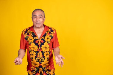 Şaşırdım, olgun bir adam canlı sarı bir arka plana karşı Hawaii gömleği giyerken omuz silkiyor.