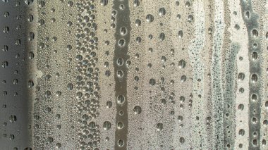 Yağmur damlaları pencereye yakın planda düşer. Yağmur, yağmurlu, depresif, kasvetli hava. Islak damla suyu. Bardağın üzerinde büyük damlalar olan su damlaları. Pencerede su damlaları ve su damlaları var..