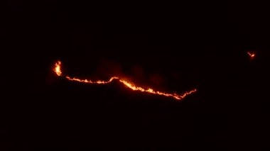 Ormanda ateş ve dumanla gece yangını. Dumanı tüten bir alevin efsanevi hava videosu. Geceleri yanan, parlayan bir ateş. İklim değişikliği, ekoloji. Karanlıkta çizgi yangını..