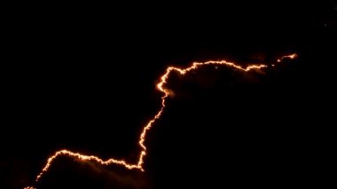 Ormanda ateş ve dumanla gece yangını. Dumanı tüten bir alevin efsanevi hava videosu. Geceleri yanan, parlayan bir ateş. İklim değişikliği, ekoloji. Karanlıkta çizgi yangını..