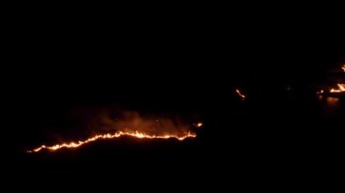 Ormanda ateş ve dumanla gece yangını. Dumanı tüten bir alevin efsanevi hava videosu. Geceleri yanan, parlayan bir ateş. İklim değişikliği, ekoloji. Karanlıkta çizgi yangını..