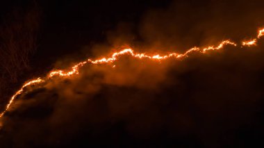 Ormanda ateş ve dumanla gece yangını. Dumanı tüten bir alevin efsanevi hava fotoğrafı. Geceleri yanan, parlayan bir ateş. İklim değişikliği, ekoloji. Karanlıkta çizgi yangını..