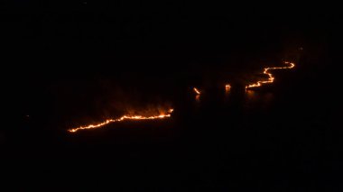 Ormanda ateş ve dumanla gece yangını. Dumanı tüten bir alevin efsanevi hava fotoğrafı. Geceleri yanan, parlayan bir ateş. İklim değişikliği, ekoloji. Karanlıkta çizgi yangını..