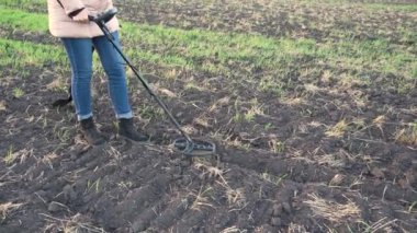 Altın detektörüyle arkeolojik ve hazine avcılığı. Yeraltında antika arayışı. Altın külçeleri üzerinde toprak araştırması. Elinde metal dedektörü ve küreği olan bir kadın.