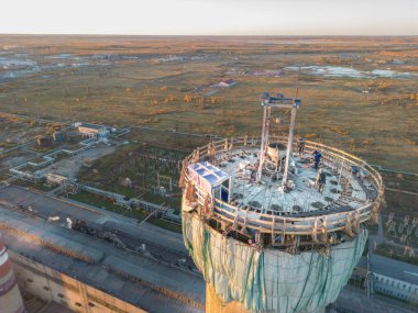 Yükseklerde tehlikeli bir iş. Bir elektrik santralinin inşaat sahası yüksek baca. Tadilat bir duman yığınıdır. Müteahhit, yüksek bir binanın bacasını onarıyor.