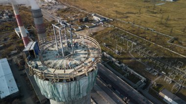 Yükseklerde tehlikeli bir iş. Bir elektrik santralinin inşaat sahası yüksek baca. Tadilat bir duman yığınıdır. Müteahhit, yüksek bir binanın bacasını onarıyor.