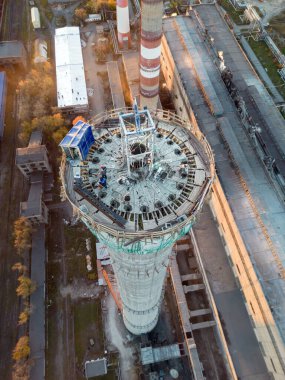 Dikey fotoğraf. Yükseklerde tehlikeli bir iş. Bir elektrik santralinin inşaat sahası baca. Tadilat baca dumanına dönüşür.