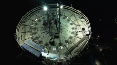 Bir çatı ekibinin çalışma yeri. Nükleer enerji santrali inşaatı. Nükleer enerji. Alacakaranlıkta aydınlatılmış inşaat alanı. Gece yüksekliğinde tehlikeli bir iş. Kask takan işçiler bir baca inşa ediyorlar.