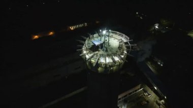 Bir çatı ekibinin çalışma yeri. Nükleer enerji santrali inşaatı. Nükleer enerji. Alacakaranlıkta aydınlatılmış inşaat alanı. Gece yüksekliğinde tehlikeli bir iş. Sert şapkalı işçiler bir baca inşa ederler.