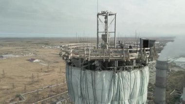 Elektrik santralinde yeni bir baca inşaatı. Yükseklerde inşaat alanı. Miğferli adamlar. Nükleer teknolojiler, nükleer santral inşaatı. Koruyucu kask takan erkek mühendisler..