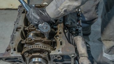 Tamirhanede oto tamircisi çalışıyor. Tamirat servisi. Garajda arabanın motoru üzerinde çalışan profesyonel tamirci. Otomobil tamircisinin eli aletli yakın.