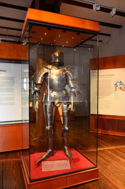 Nuremberg, Almanya 10.17.2019: Titizlikle cilalanmış çelikten yapılmış etkileyici bir ortaçağ zırhı, dik duruyor ve müze vitrininde sergileniyor.