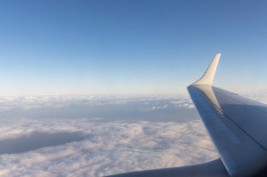 kalın bulutlar ve mavi gökyüzü arka plan üzerinde jet uçak kanadının görünümü.