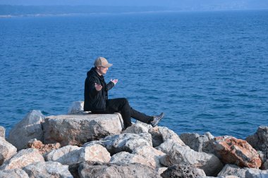 Uzun ve zorlu bir yolculuktan sonra nihayet Adriyatik Denizi kıyısında sakin ve güzel bir yere ulaşan genç bir adamın neşeli duyguları. Parlak kış güneşi taşları ısıtıyor ve sahilde rahatça kalabilmesini sağlıyor..