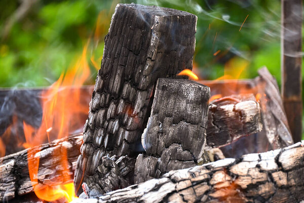 A brightly burning campfire made from stacked oak firewood turning into coals for cooking picnic food.