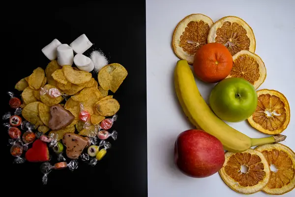 Siyah arka planda, beyaz arka planda cipsler, şekerler, şekerler ve kurabiyeler bulunur: muz, mandalina elması ve greyfurt cipsi. konsept: sağlıklı yaşam tarzı, sağlıklı yemek, diyet, kalori değil.