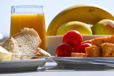 Taze ekmek, tereyağı, peynir ve bir bardak taze meyve suyu ve meyveli domateslerle kaplayın..