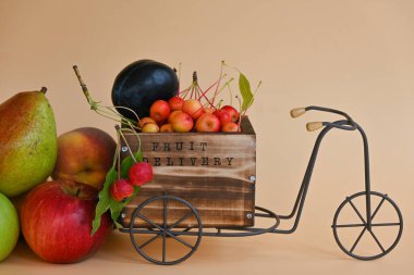 Şeftali arka planında yazı için yeri olan dekoratif metal bir bisiklet mevsimlik meyvelerle dolu ahşap bir sepet ile: elma, erik, şeftali, armut ve cennet elmaları. Olası konsept: dağıtım, çiftçi pazarı, reklam